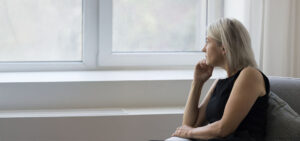 Mature woman sitting near a window in natural light, representing consideration of non-medication treatment options for depression, anxiety, and OCD